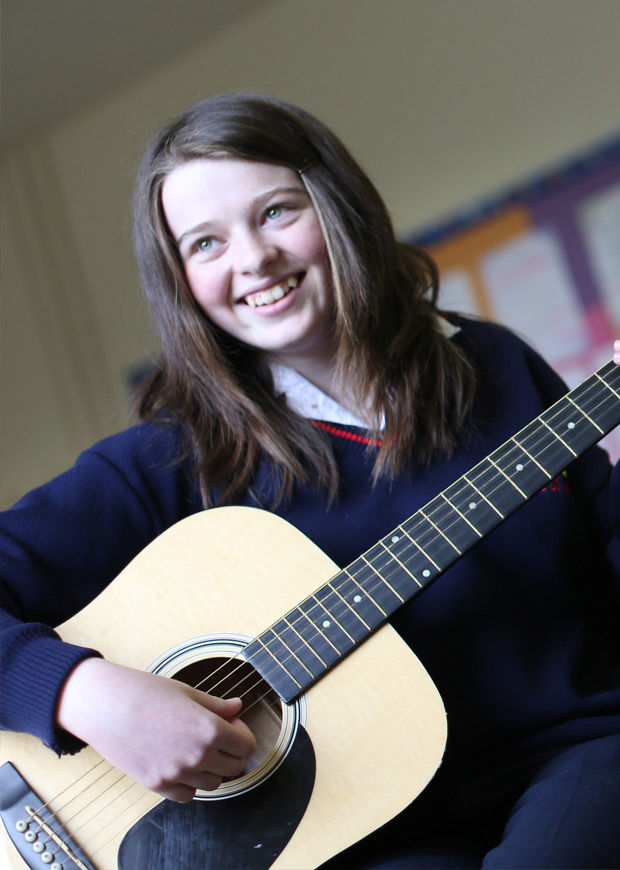 Student playing guitar and smiling