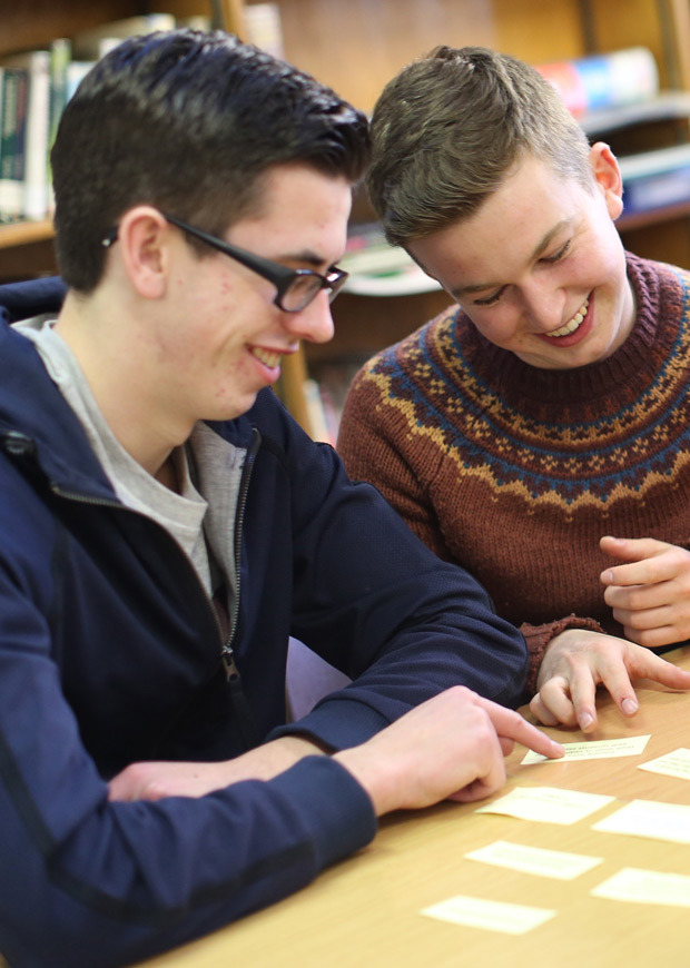 Two students laughing and working together at a table