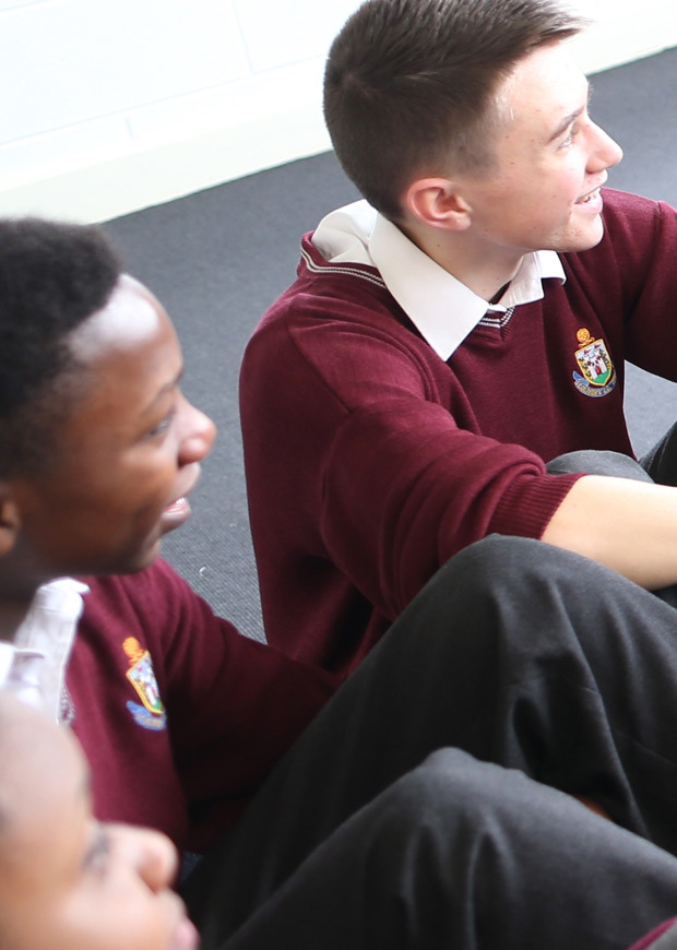 Two male students sitting on the floor and looking in the same direction