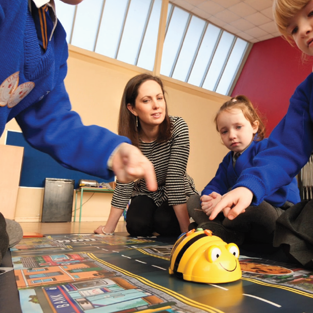 Teacher and children working with Beebots