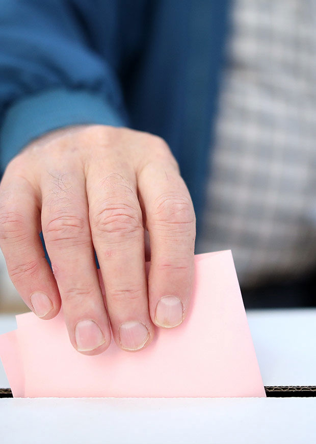 Portrait shot of a hand putting a polling card into a ballot box