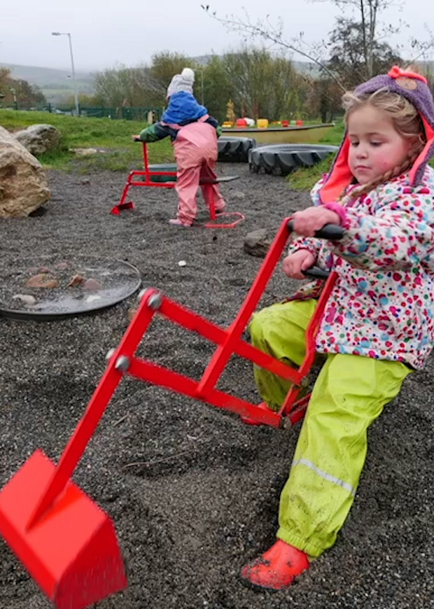 Young girl on miniature digger in gravel