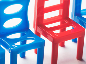 Close up image of a row of blue plastic chairs with one red chair standing out